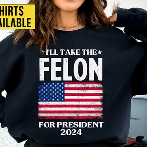 May include: Black sweatshirt with a distressed American flag design and the text "I'll take the felon for president 2024".
