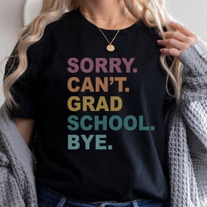 Może przedstawiać: Czarny T-shirt z napisem "SORRY. CAN'T. GRAD SCHOOL. BYE." w tęczowym gradiencie kolor&oacute;w.