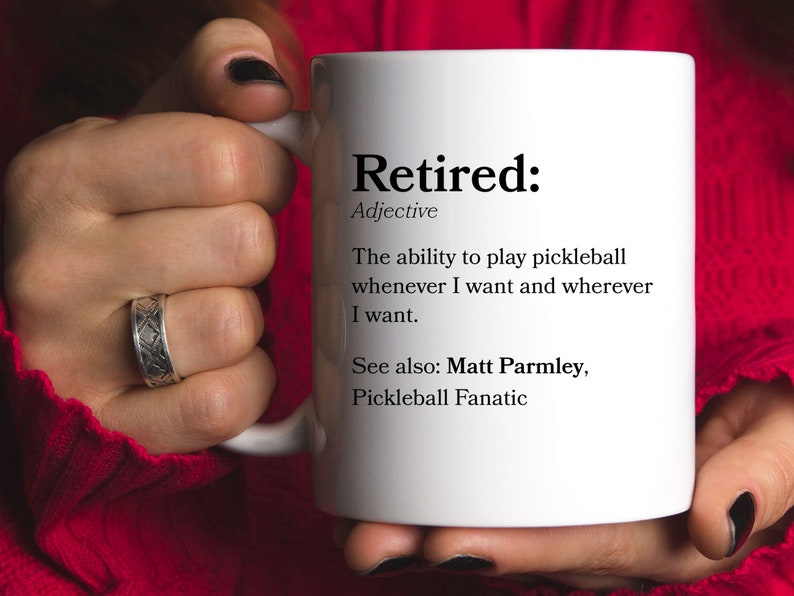 May include: White coffee mug with the word "Retired" defined as "The ability to play pickleball whenever I want and wherever I want."  The text also says "See also: Matt Parmley, Pickleball Fanatic."