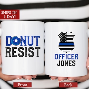 May include: White ceramic coffee mug with a blue donut and the text "Donut Resist" on the front. The back of the mug has a black and blue shield with a thin blue line and the text "Officer Jones".