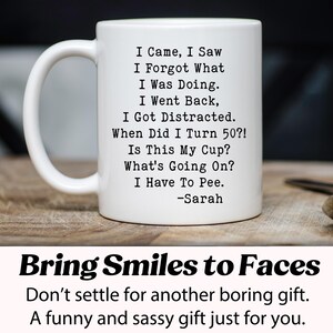 May include: White ceramic mug with a black humorous quote: "I Came, I Saw, I Forgot What I Was Doing..." and "I Have To Pee." The mug also includes the name "-Sarah." The mug is on a wooden surface. The bottom of the image says "Bring Smiles to Faces."