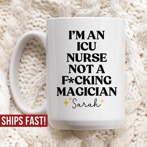 Może przedstawiać: Biały ceramiczny kubek z dużym uchwytem. Kubek zawiera tekst "I'M AN ICU NURSE NOT A F*CKING MAGICIAN" w kolorze czarnym, z imieniem "Sarah" i gwiazdkami. Kubek stoi na białej dzianinowej powierzchni.