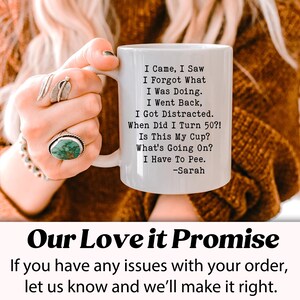 May include: White ceramic mug with black text: "I Came, I Saw, I Forgot What I Was Doing. I Went Back, I Got Distracted. When Did I Turn 50?! Is This My Cup? What's Going On? I Have To Pee." -Sarah. The mug is held by a person.
