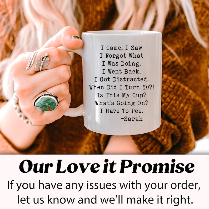 May include: White ceramic mug with black text: "I Came, I Saw, I Forgot What I Was Doing. I Went Back, I Got Distracted. When Did I Turn 50?! Is This My Cup? What's Going On? I Have To Pee." -Sarah. The mug is held by a person.