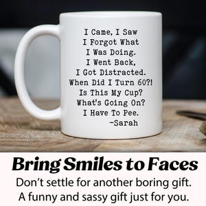 May include: White ceramic mug with a black humorous quote: "I Came, I Saw, I Forgot What I Was Doing..." and "When Did I Turn 60?!" The mug has a curved handle and is on a wooden surface. The text "Bring Smiles to Faces" is below the mug.