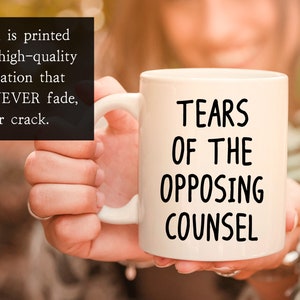 May include: White ceramic coffee mug with black text that reads "Tears of the Opposing Counsel".