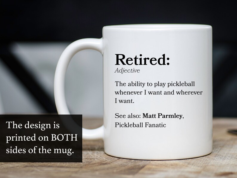 May include: White ceramic coffee mug with a black design that says "Retired: Adjective The ability to play pickleball whenever I want and wherever I want. See also: Matt Parmley, Pickleball Fanatic"
