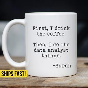 May include: White ceramic coffee mug with black text that reads "First, I drink the coffee. Then, I do the data analyst things. -Sarah"