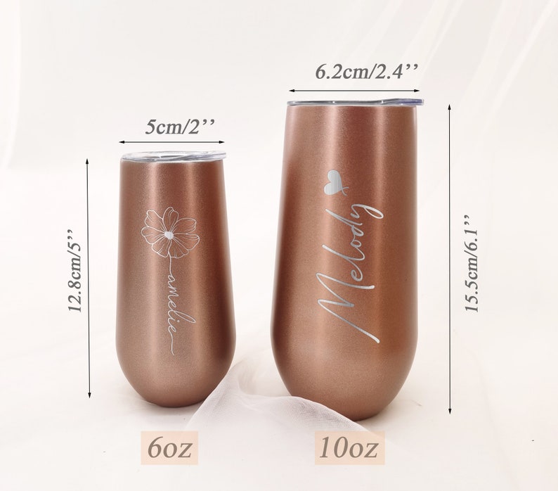 May include: Two rose gold stainless steel tumblers with personalized engravings. The smaller tumbler is 6 ounces and engraved with "amelie" and a flower. The larger tumbler is 10 ounces and engraved with "Melody" and a heart.