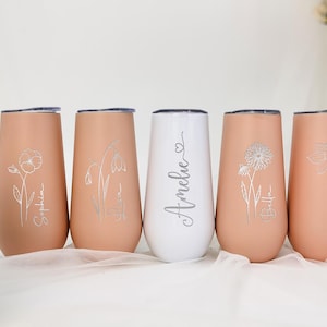May include: Five personalized stainless steel tumblers with floral designs and names. The tumblers are in shades of pink and white.