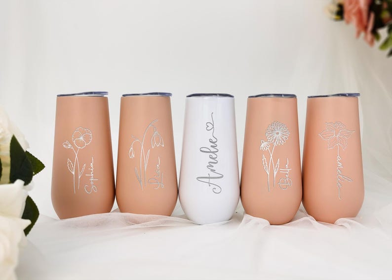 May include: Five personalized stainless steel tumblers with floral designs and names. The tumblers are in shades of pink and white.