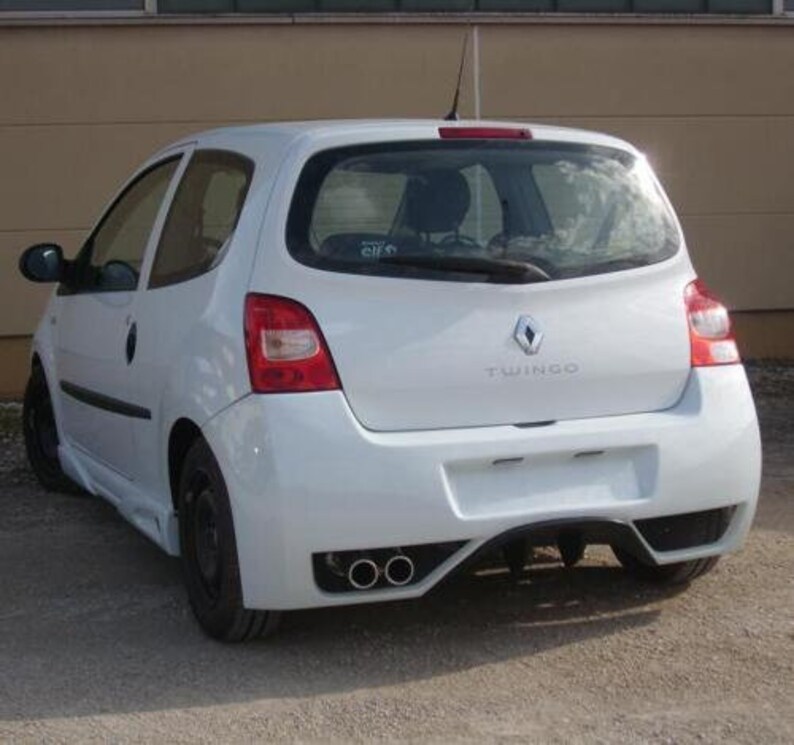 Puede incluir: Un Renault Twingo blanco, un autom&oacute;vil hatchback, con un parachoques trasero que tiene dos tubos de escape. El coche tiene un logotipo de Renault plateado y la palabra "Twingo" escrita en la parte trasera.