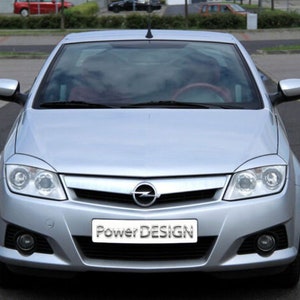 May include: A silver Opel Astra with a black grille and the text "Power Design" on the front bumper.