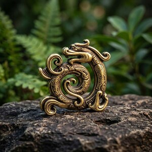 Puede incluir: Un adorno de metal color lat&oacute;n con forma de drag&oacute;n enroscado con patrones intrincados y grabados geom&eacute;tricos. La figura del drag&oacute;n presenta una cabeza prominente con cuernos curvos y un cuerpo largo y sinuoso que forma una espiral circular.
