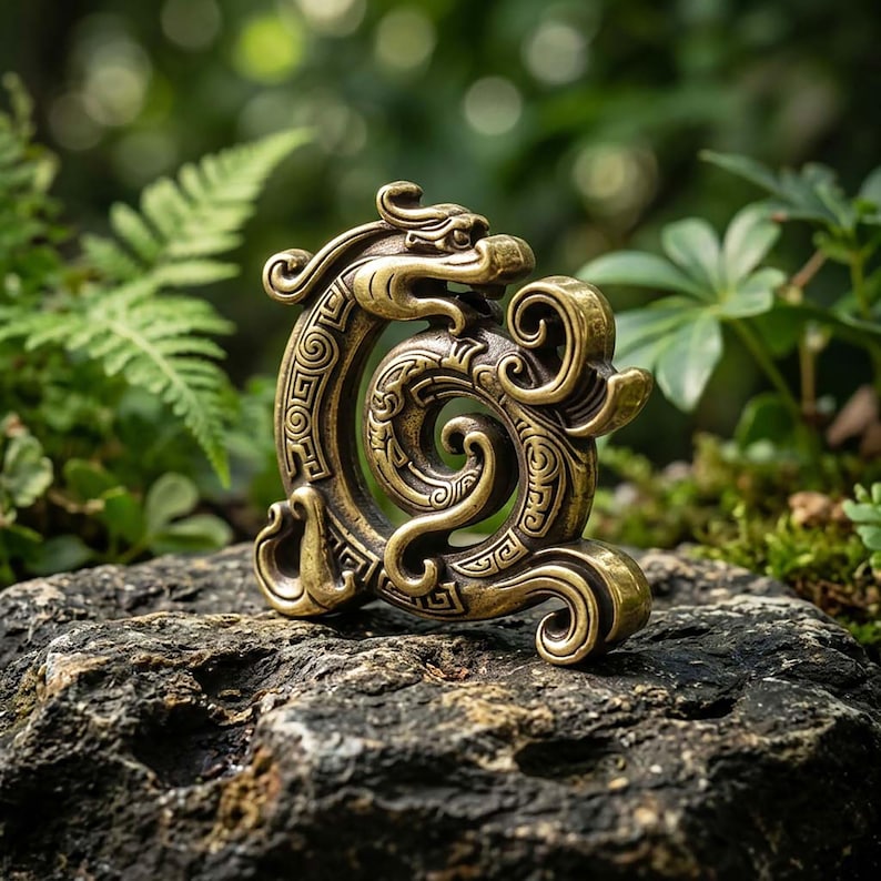 Puede incluir: Un adorno de metal color lat&oacute;n con forma de drag&oacute;n enroscado con intrincados patrones geom&eacute;tricos repetitivos grabados en su superficie. La escultura presenta un cuerpo curvo y serpentino con detalles estilizados de cabeza y cola.