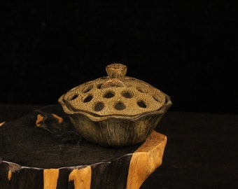May include: A green ceramic incense burner shaped like a lotus flower with a lid. The burner is sitting on a wooden stand.