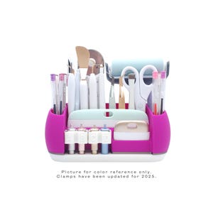 May include: A pink and white craft organizer filled with various tools, including scissors, pens, and a roller. The organizer has a mint green top and a white base. Text at the bottom reads "Picture for color reference only. Clamps have been updated for 2025."