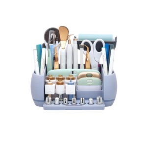 May include: A light blue craft organizer filled with various tools. The organizer has multiple compartments holding pens, scissors, tweezers, and other crafting essentials. Gold and white tools are visible, along with a blue roller and a variety of small, gold-topped containers.