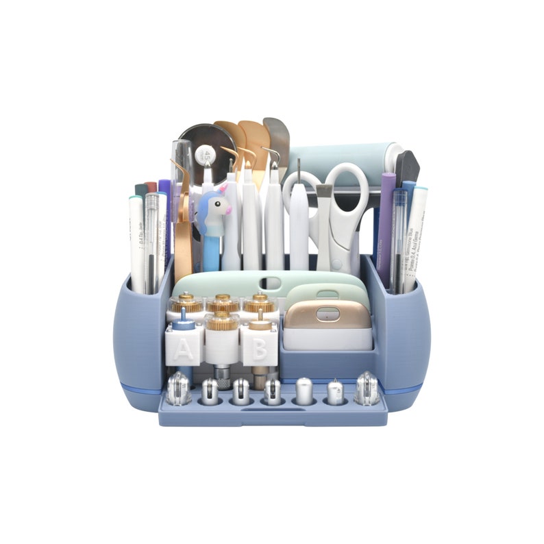 May include: A blue craft organizer filled with various tools, including pens, scissors, and cutting blades. The organizer has multiple compartments and a variety of craft supplies, perfect for a crafter's workspace.