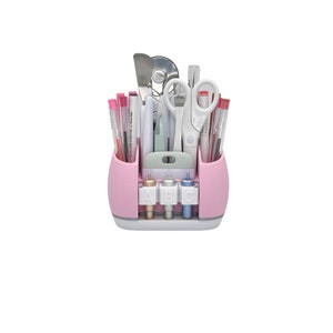 May include: A pink craft organizer filled with various tools, including pens, scissors, and a spatula. The organizer has multiple compartments and a white base. The front features three gold, white, and blue tools labeled "ABC".