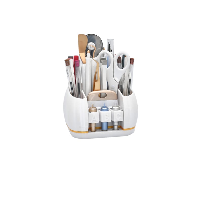 May include: A white craft organizer with gold trim, filled with various tools including scissors, pens, and spatulas. The organizer has three sections for tools and a base with three labeled compartments. The tools are arranged neatly.