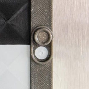 May include: Close-up of a gray and black chessboard with a white and gray plastic piece on the side.