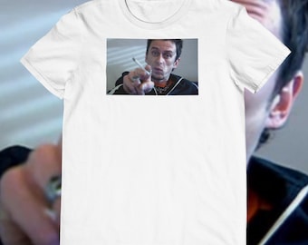 Op de afbeelding: Wit T-shirt met een rechthoekige afbeelding van een man die wijst, met een sigaret in zijn hand. De man draagt een zwart jack met witte strepen en een zilveren ring. Het shirt is gemaakt van een zacht, comfortabel materiaal.