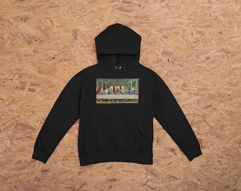 Op de afbeelding: Zwarte hoodie met een voorzak en een kleurrijke afbeelding van het Laatste Avondmaal. De afbeelding toont Jezus en zijn discipelen aan een tafel. De hoodie is gemaakt van een zacht materiaal.