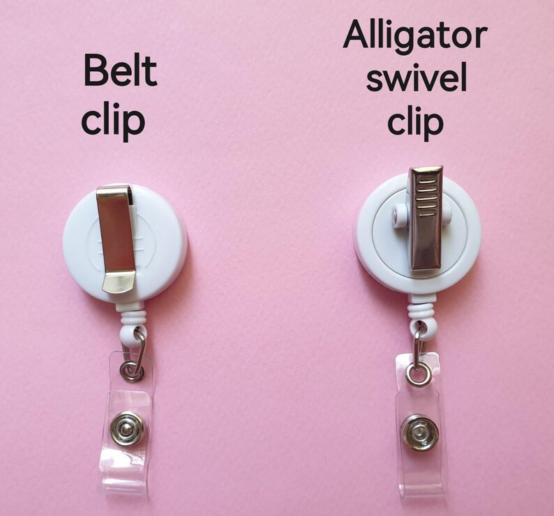 May include: Two white retractable badge holders with different clips. The left holder has a belt clip and the right holder has an alligator swivel clip. Both holders have a clear plastic strap.
