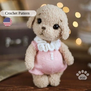 May include: Crochet pattern for a small, beige amigurumi poodle wearing a pink dress with a white crocheted collar. The pattern is available as a PDF download. Crochet Pattern.