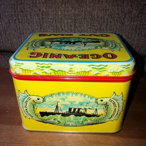 May include: A yellow square tin with a red and blue border. The tin has a picture of a ship on the front with the words "Ocean Wave" and "Detroit, Michigan" on the sides of the ship. The words "Southern Dillon Co." are on the left side of the ship and the words "Detroit, Michigan" are on the right side of the ship.