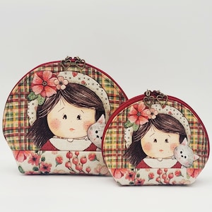 Peut inclure: Deux trousses de toilette en tissu rouge et blanc avec un motif à carreaux et des accents floraux. Chaque trousse présente une fille de dessin animé avec un chat.