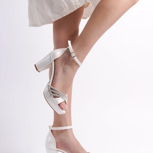 May include: White platform heels with a rhinestone strap and ankle strap. The heels are about 4 inches tall.