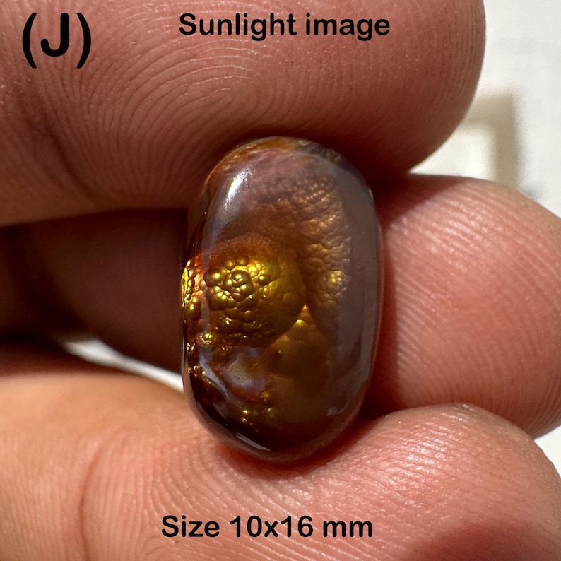 May include: A polished, oval-shaped gemstone with a rich, brown and gold color. The stone has a unique, textured surface with a size of approximately 0.4 x 0.6 inches. The image is labeled "Sunlight image" and "Size 10x16 mm".