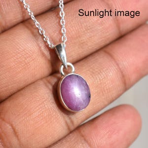 May include: A silver chain necklace with a pendant featuring a pink oval gemstone. The pendant is set in a silver bezel.