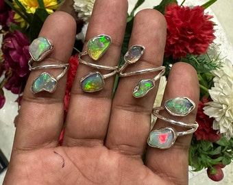 May include: Five silver rings with opal gemstones. Each ring features a unique opal with a different colour and pattern. The opals are set in a simple silver band.