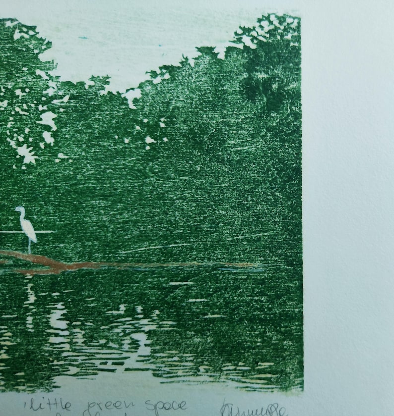 May include: A green-toned print on paper featuring a white bird standing on a brown branch over water, with dense foliage in the background. The text 'little green space' is written in pencil at the bottom left, with a signature on the bottom right.