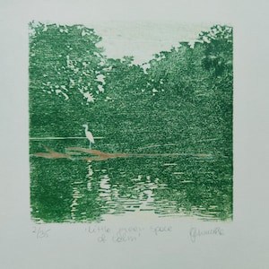 May include: A green-toned print featuring a white egret standing on a brown log in a body of water surrounded by trees. The text "little green space of calm" is written below the image, along with the edition number 2/35 and a signature.