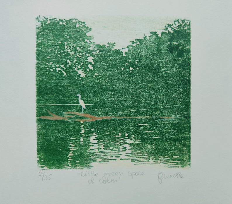 May include: A green-toned print featuring a white egret standing on a brown log in a body of water surrounded by trees. The text "little green space of calm" is written below the image, along with the edition number 2/35 and a signature.
