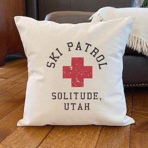 May include: White pillow with a red cross and the text "Ski Patrol Solitude, Utah" in black.