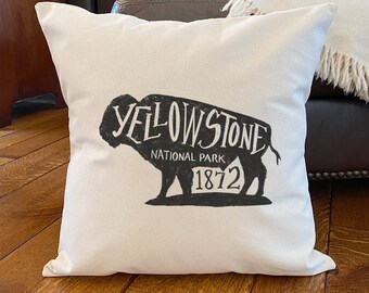May include: White pillow with a black silhouette of a buffalo with the text "Yellowstone National Park 1872" printed on it.