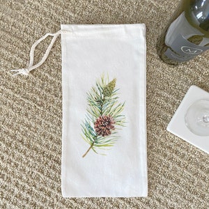 May include: White cotton wine bottle bag with a brown pine cone and green pine needles printed on the front.
