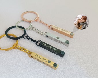 May include: Four personalized bar keychains in gold, black, silver, and rose gold. Each keychain has a different message engraved, including "I love you," "Forever love," and "Love you mummy." Each bar has a small, green gem.
