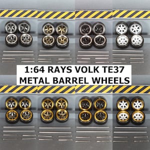 May include: A collection of 1:64 scale model car wheels in various styles. The wheels have black tires and metal barrel rims in silver, gold, and black. The text "1:64 RAYS VOLK TE37 METAL BARREL WHEELS" is displayed.