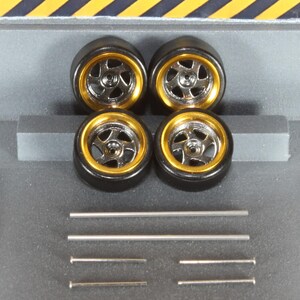 May include: Four model car tyres with gold rims and silver spokes. Several silver metal rods and pins are also included. The tyres are arranged in a square, with the rods and pins below.