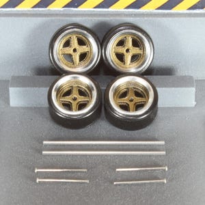 May include: Four black model car wheels with gold-colored centers and silver rims. Also included are six silver metal rods of varying lengths. The wheels are arranged in a square, with the rods below.