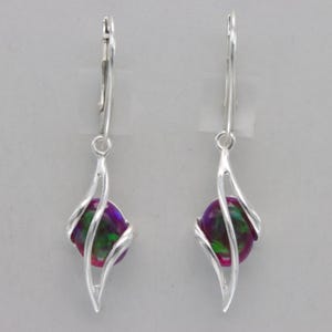May include: Silver dangle earrings with a green, purple, and iridescent round stone set in a silver swirl design.