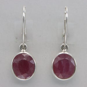 May include: A pair of silver dangle earrings with oval-shaped pink gemstones.