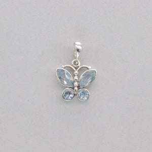 May include: A silver butterfly charm with light blue topaz gemstones. The charm is perfect for adding a touch of whimsy to any jewelry piece.