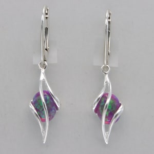 May include: Silver dangle earrings with a purple and green opal stone set in a twisted silver design.